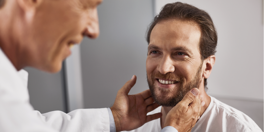 man having his thyroid glands examined by a doctor