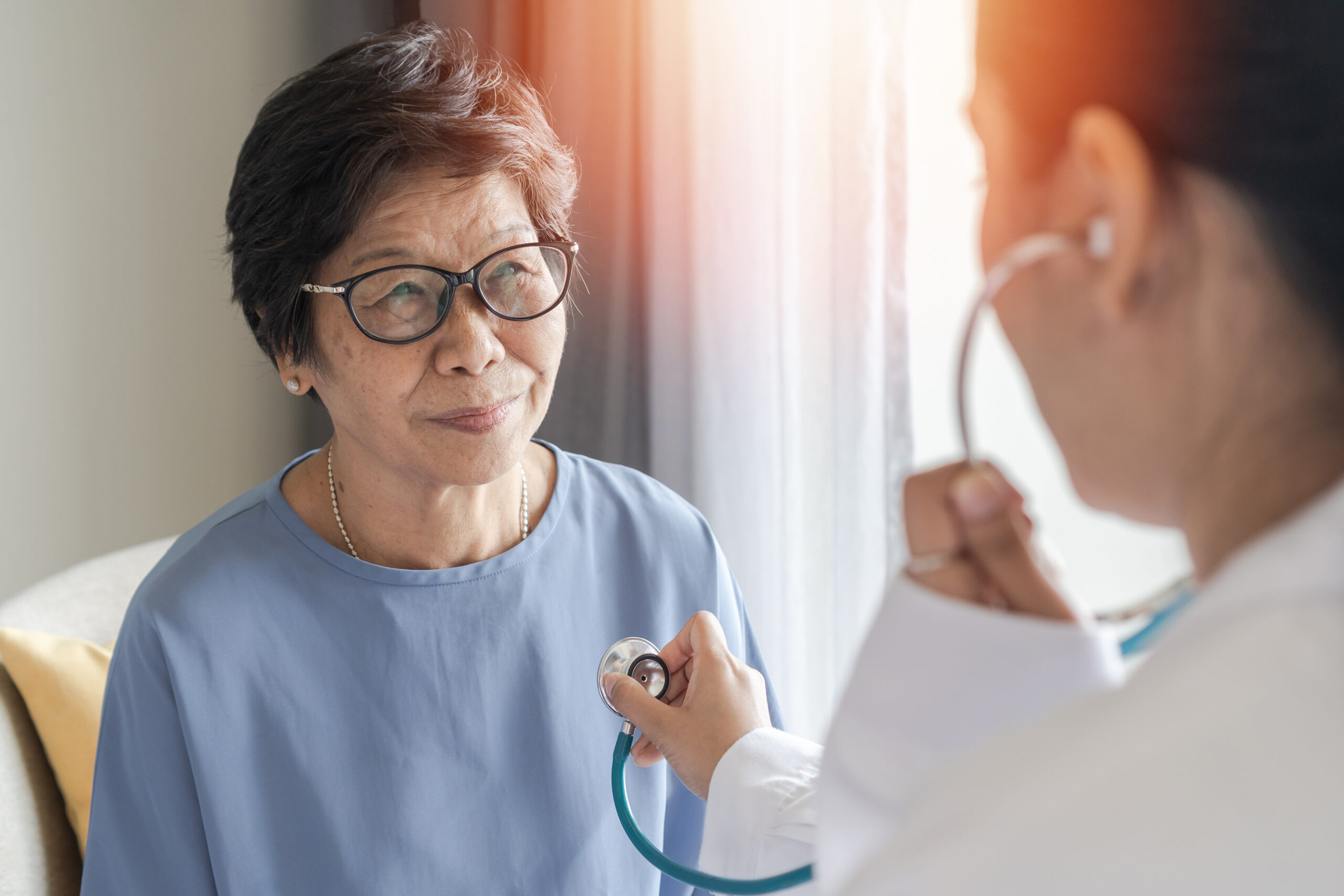 Happy elderly patient with medical health checkup with cardiologist or geriatric doctor. Senior old aging woman with coronary artery heart disease or cardiac illness check-up in clinic doctor examining a patient's heartbeat